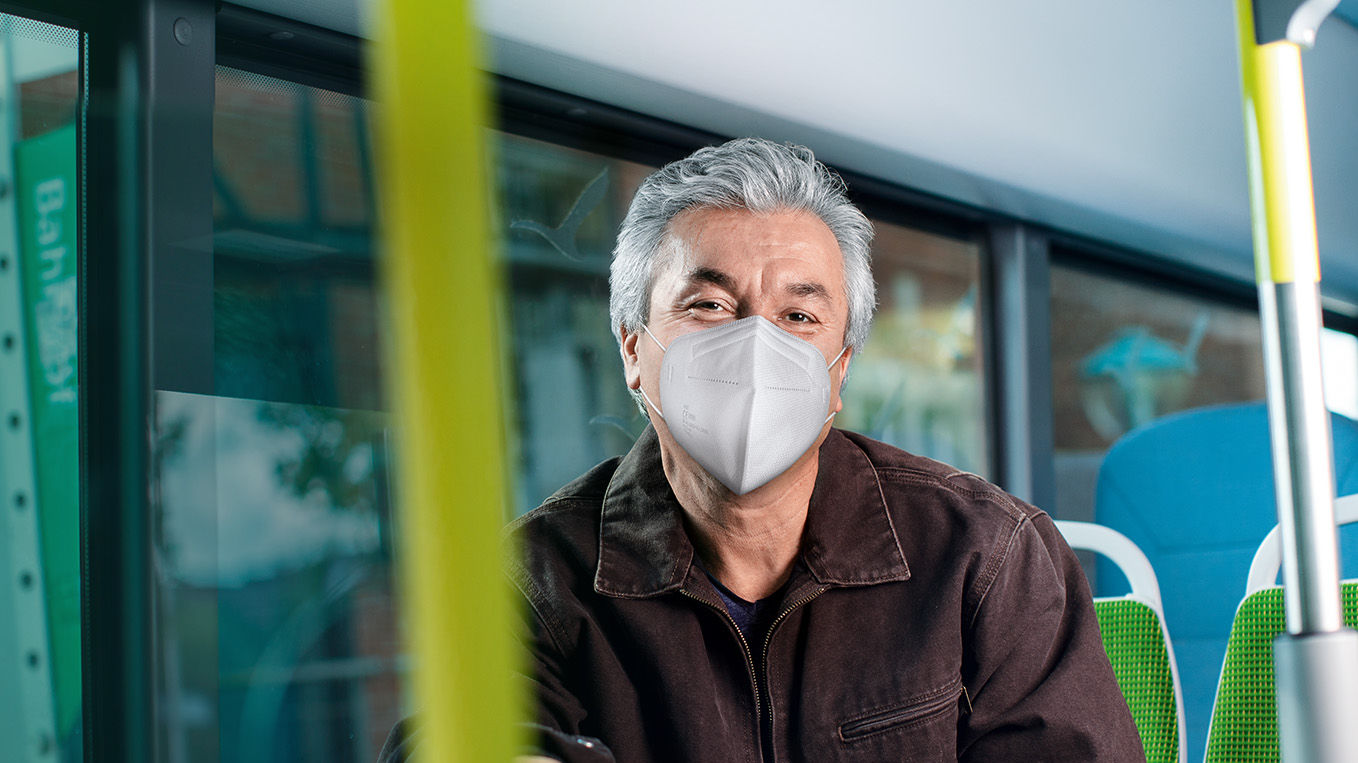 Älterer Herr sitzt mit FFP2-Maske im Bus.