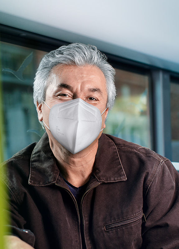 Älterer Herr sitzt mit FFP2-Maske im Bus.