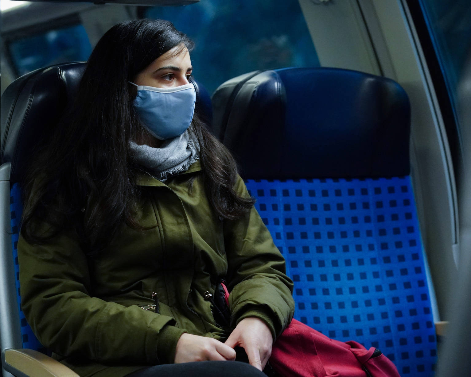 Frau trägt Gesichtsmaske und fährt Bahn