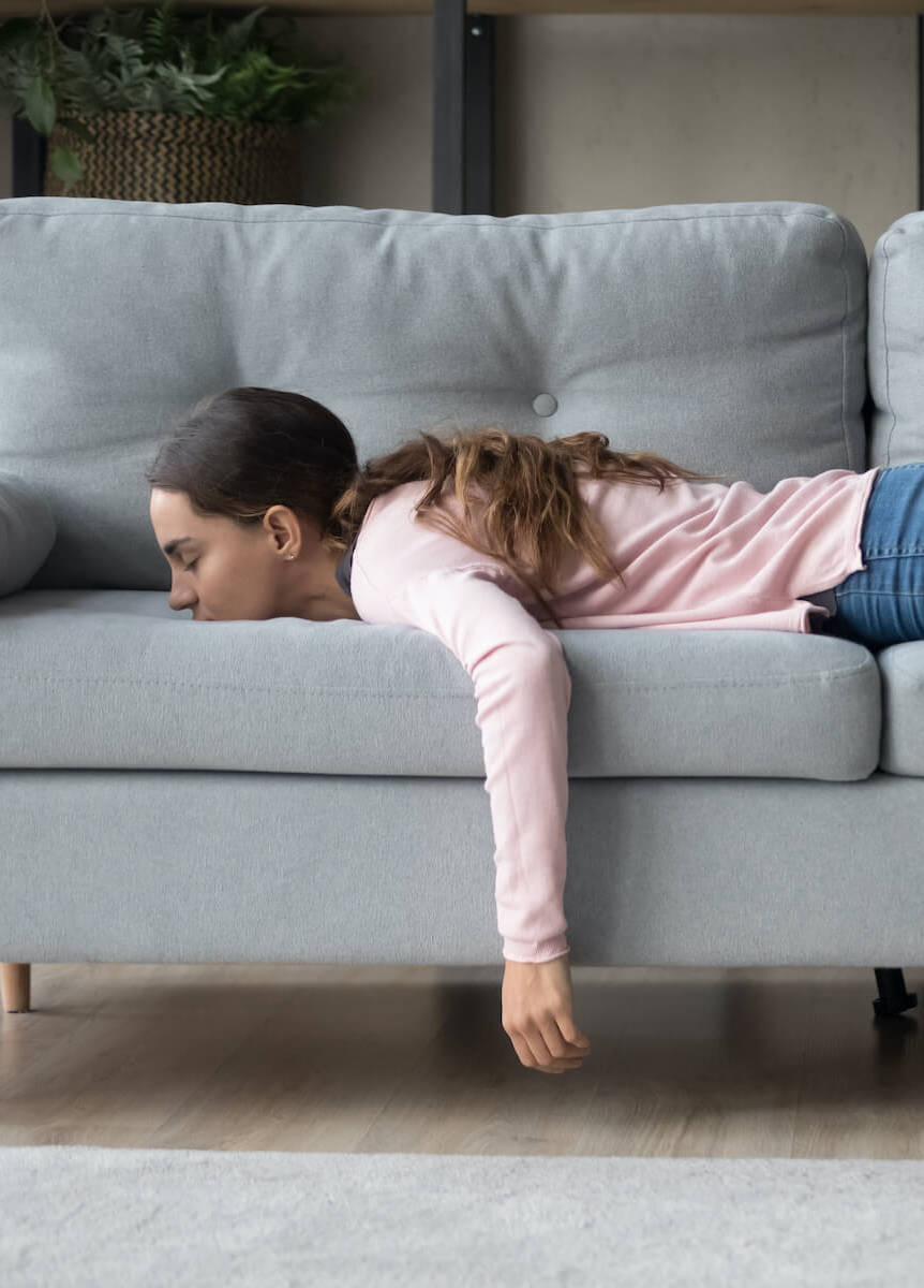 Frau liegt erschöpft auf dem Sofa