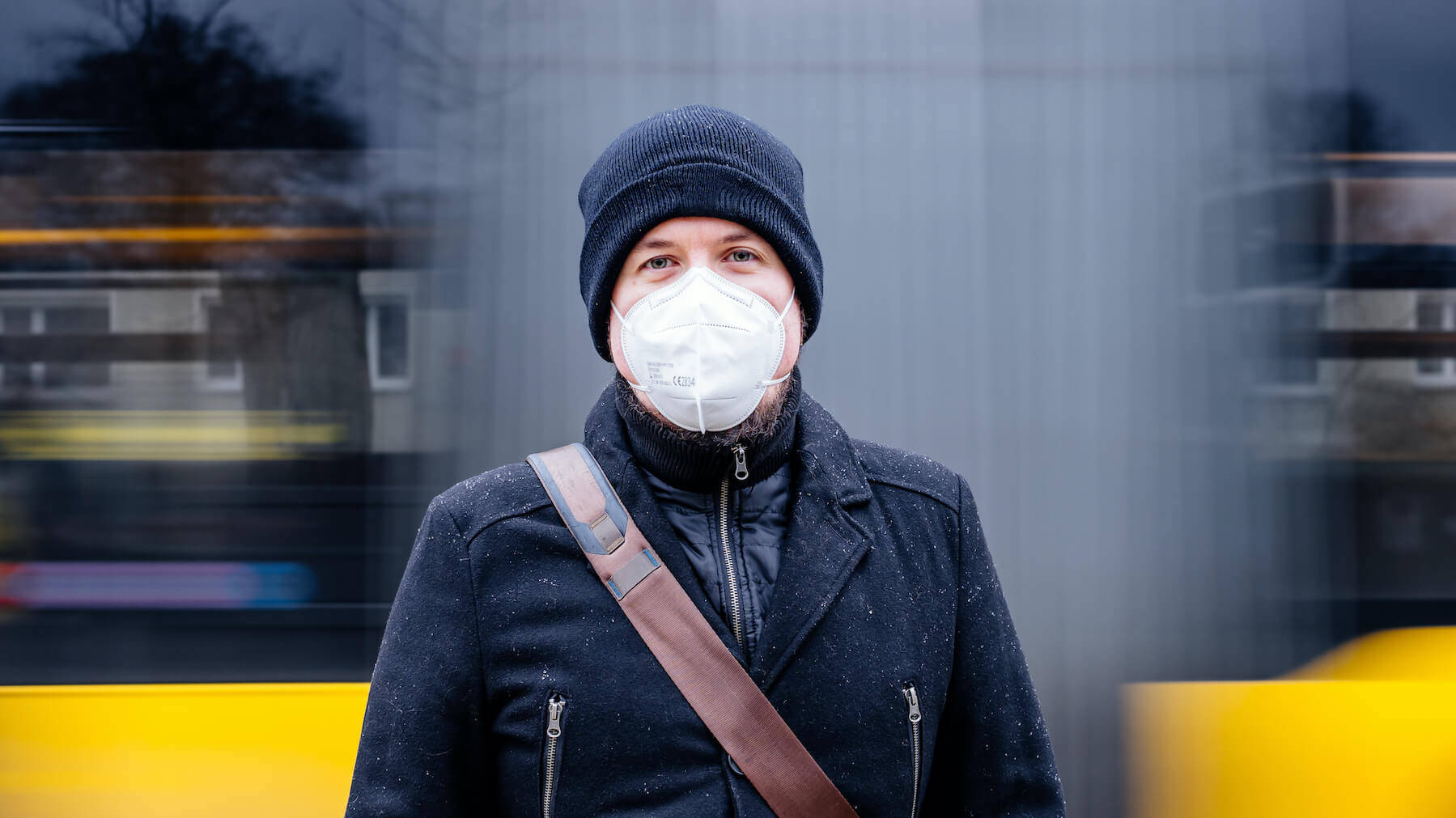 Mann mit FFP2-Maske steht vor einem fahrenden Bus