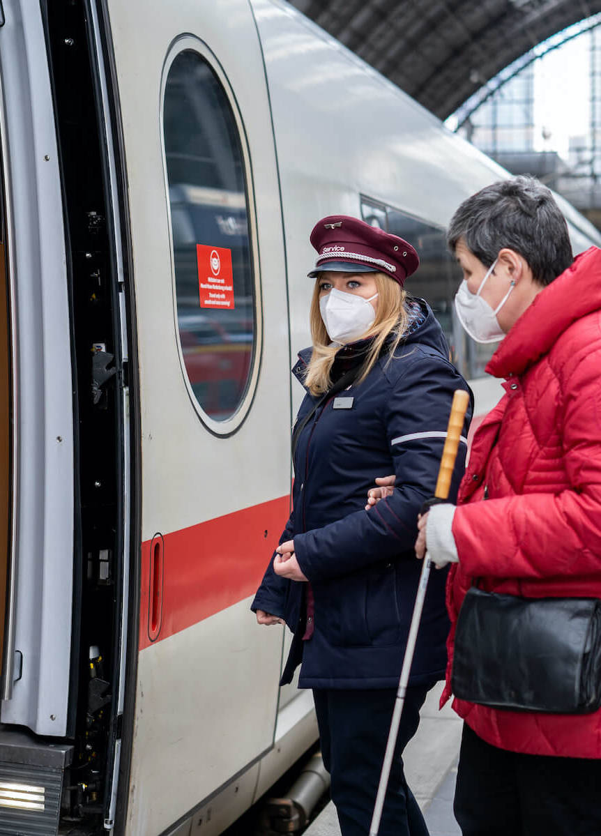 DB-Mitarbeiterin hilft einer Kundin beim Einstieg in einen ICE