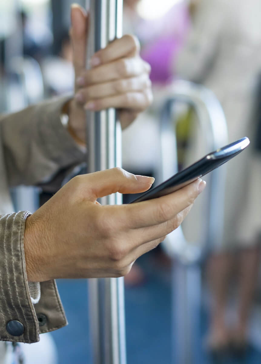 Eine Frau fährt Bus und schaut dabei auf ihr Smartphone