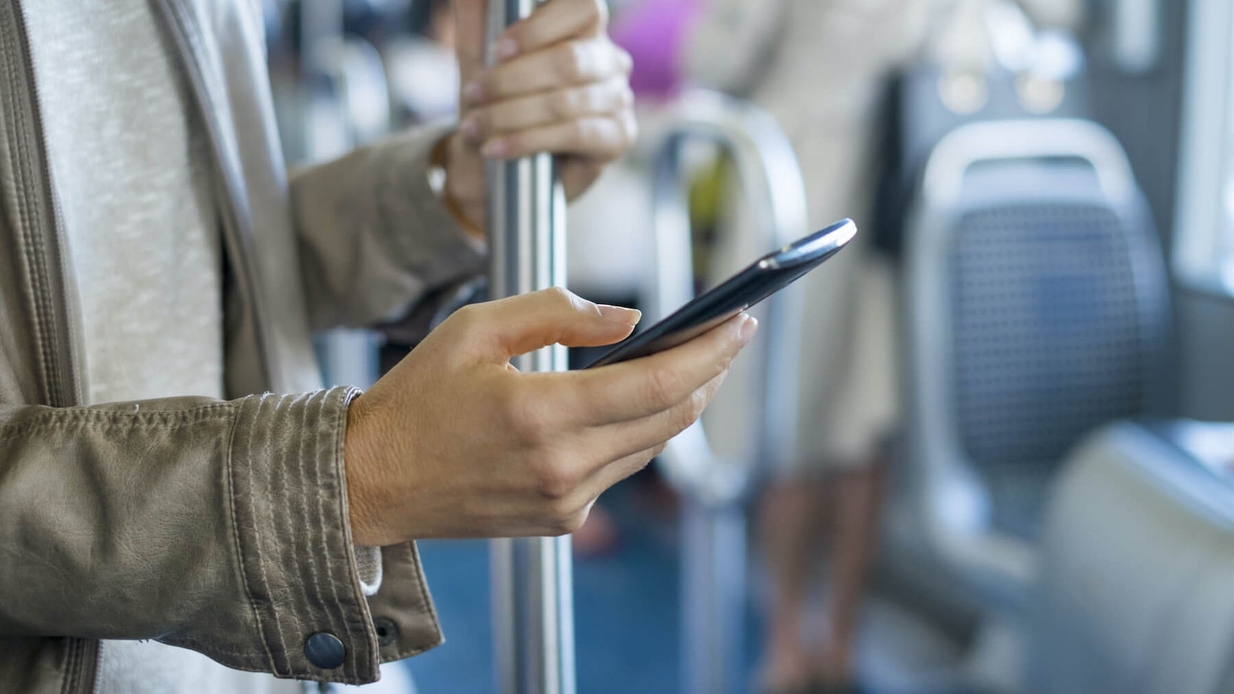 Eine Frau fährt Bus und schaut dabei auf ihr Smartphone