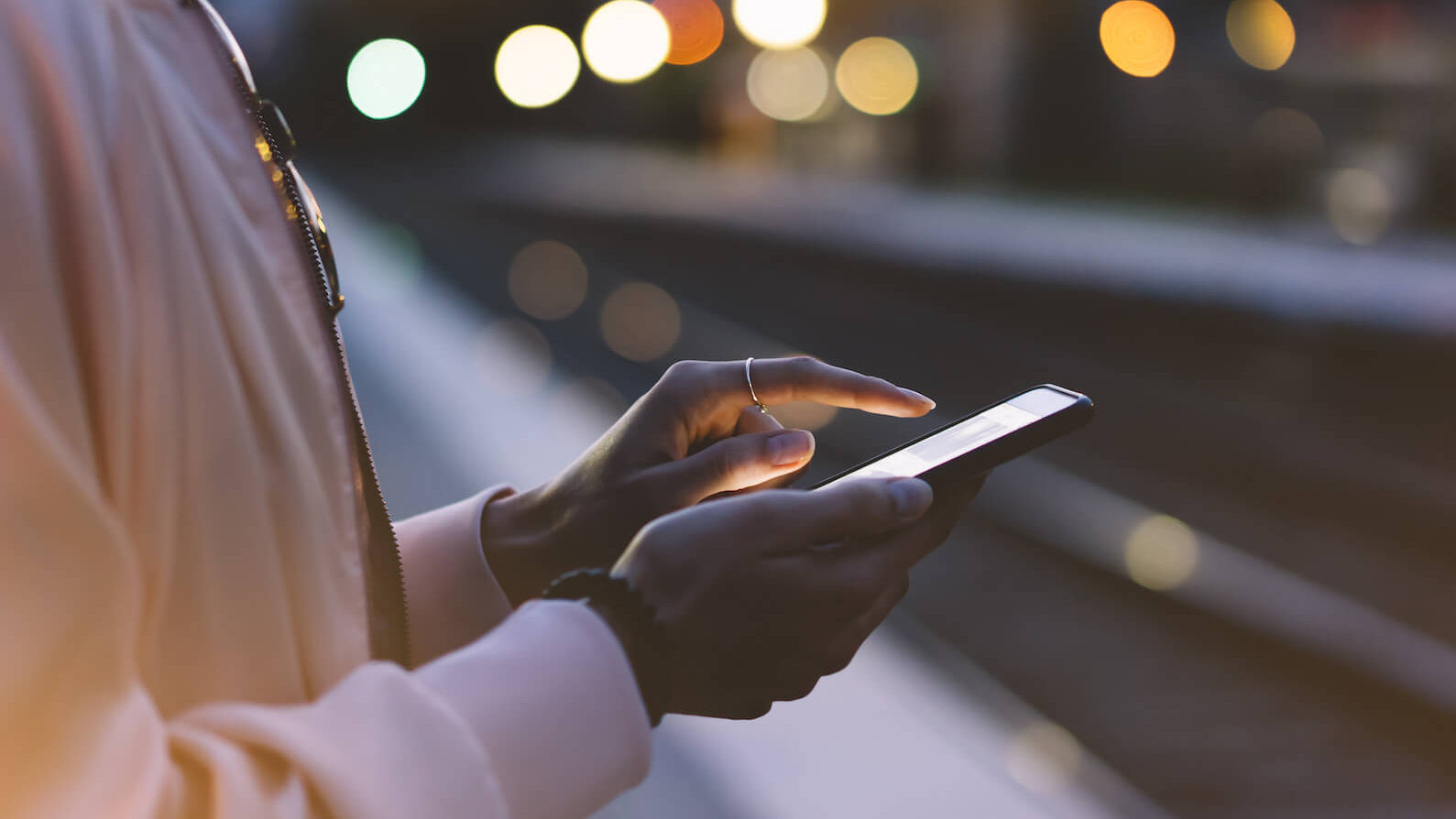 Fraiu steht mit ihrem Handy am Bahngleis